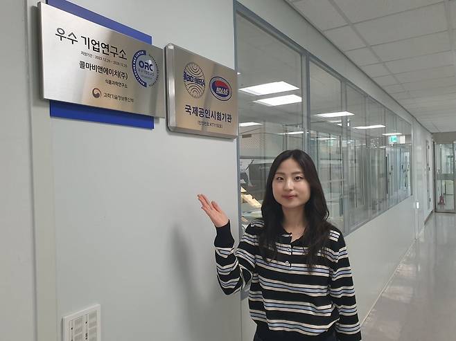 윤수민 사원이 과기정통부 선정 우수기업연구소 현판을 가리키고 있다. 윤현주 기자