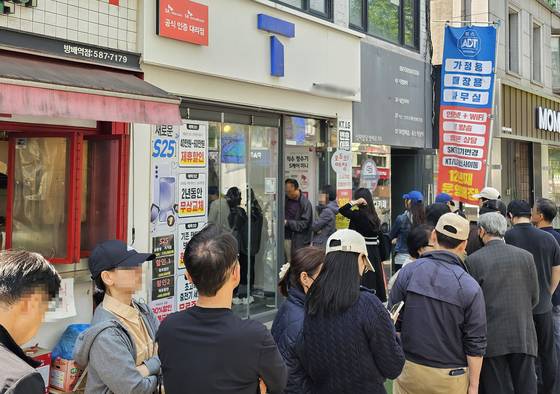Customers wait in line outside an SK Telecom store in Seoul on April 26 to change their SIM cards. [YONHAP]