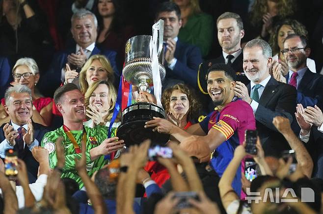[세비야=AP/뉴시스] FC 바르셀로나 선수들이 27일(현지 시간) 스페인 세비야의 에스타디오 델 라 카르투하에서 열린 2024-25 코파 델 레이(국왕컵) 정상에 올라 트로피를 들고 환호하고 있다. 바르셀로나는 결승전에서 레알 마드리드와 연장 끝 3-2로 승리하고 우승컵을 들어 올렸다. 2025.04.27.
