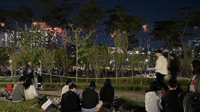 26일 세종중앙공원과 호수공원 일원에서 열린 2025 세종낙화축제장을 찾은 시민들이 낙화를 감상하고 있다. 작년보다 2배 많은 1만개의 낙화봉을 태웠지만, 주변 가로등 조명이 유지되면서 낙화의 아름다움은 반감했다는 평가를 받았다. 불꽃 뒤로 정부세종청사와 국립세종도서관 등 건물 조명이 비친다. 정민승 기자