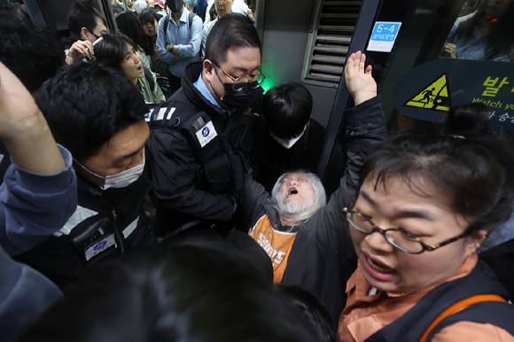 박경석 전국장애인차별철폐연대(전장연) 대표가 지난 21일 서울 지하철 4호선 혜화역 승강장에서 시위를 벌이던 중 이를 저지하던 서울교통공사 관계자와 충돌하고 있다. [사진=연합뉴스]