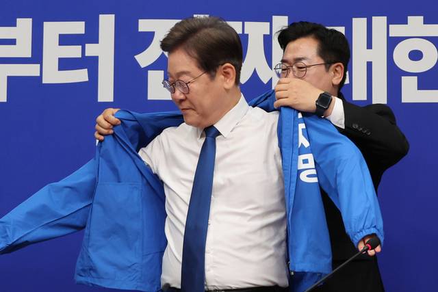 ▲ 더불어민주당 박찬대 당대표 직무대행 겸 원내대표가 28일 서울 여의도 국회에서 열린 최고위원회의에서 이재명 대선 후보에게 선거운동용 파란색 점퍼를 입혀주고 있다. 연합뉴스