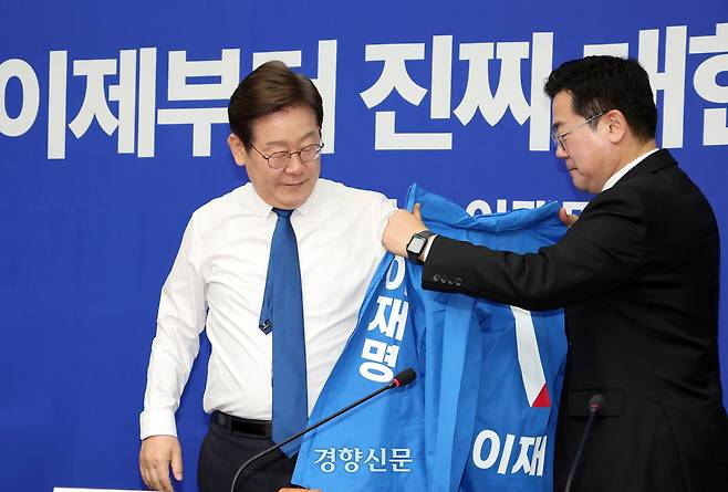 박찬대 더불어민주당 대표 직무대행 겸 원내대표(오른쪽)가 28일 국회에서 열린 최고위원회의에서 당 경선에서 승리한 이재명 대선 후보에게 당점퍼를 입혀주고 있다. 박민규 선임기자