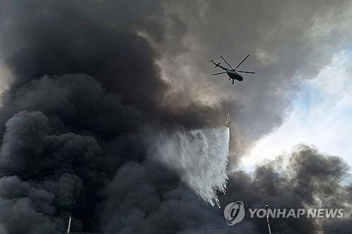 샤히드라자이 항구 상공 날며 진화하는 소방헬기 [AFP=연합뉴스. 재판매 및 DB 금지]