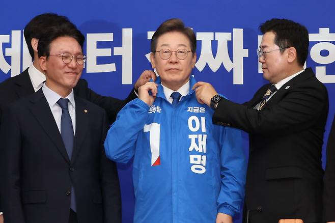 더불어민주당 박찬대 당대표 직무대행 겸 원내대표가 28일 서울 여의도 국회에서 열린 최고위원회의에서 이재명 대선 후보에게 선거운동용 파란색 점퍼를 입혀주고 있다. (사진=연합뉴스)