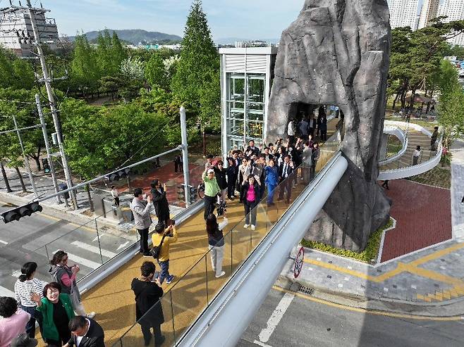 선돌공원과 선돌마당공원 사이에 놓인 선돌보도교 위에서 방문객들이 촬영용 드론을 향해 손을 흔들고 있다. 달서구 제공