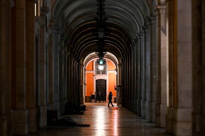 2025년 4월 28일, 대규모 정전 이후 조명이 복구된 리스본 코메르시우 광장에서 한 시민이 걷고 있다. 이번 정전은 이베리아반도와 프랑스 남부 전역을 암흑에 빠뜨렸다. 페드로 산체스 스페인 총리는 이날 기자회견에서 “모든 가능성을 열어두고 정전 원인을 분석하고 있다”고 밝혔다. [AFP=연합]