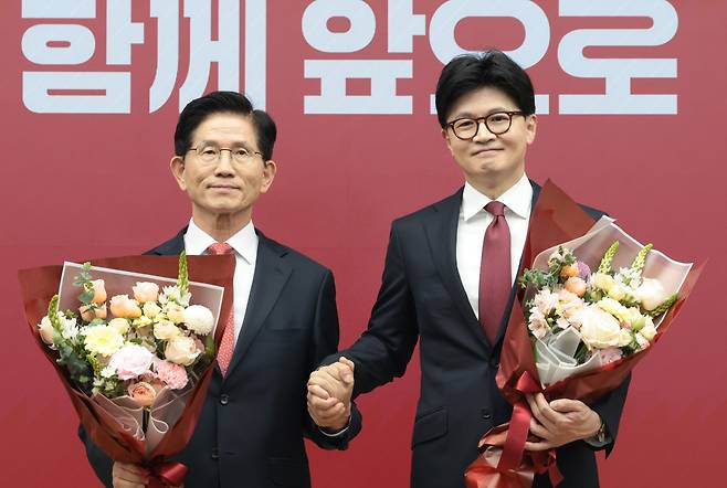 29일 국민의힘 대선 경선 결선에 진출한 김문수(왼쪽)·한동훈 후보가 서울 여의도 국민의힘 당사에서 경선 결과 발표 후 꽃다발을 들고 손을 맞잡고 있다./국회사진기자단