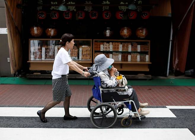 치매환자가 100만명에 육박하면서 이들 환자들의 의사결정이 어려워 처분이 불가능한 자산, 이른바 ‘치매머니’가 500조원에 이른다. 이로 인해 국내 경제에도 미칠 파장이 커질 전망이다. 사진은 일본 도쿄 스가모구 거리에서 한 노인의 휠체어를 밀어주고 있는 여인의 모습  [로이터]