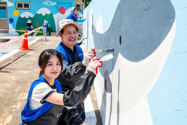 이용욱(왼쪽) 기획재정부 복권위원회 사무처장과 행복공감봉사단 단장을 맡은 박하선 배우가 29일 서울 은평구 '꿈나무마을 파란꿈터' 외벽에 벽화를 채색하고 있다. 사진 제공=동행복권