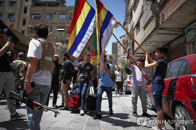 충돌 벌어진 드루즈 마을 (자라마나 AP=연합뉴스) 29일(현지시간) 시리아 수도 다마스쿠스 외곽 자라마나 마을의 아이들이 드루즈교를 상징하는 깃발을 들고 있다. 2025.4.29 photo@yna.co.kr