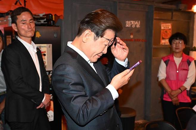 더불어민주당 이재명 대선 후보가 1일 서울 종로구의 한 포차 식당에서 \\\'당신의 하루를 만드는, 보이지 않는 영웅들\\\'이란 주제로 배달 라이더, 택배 기사 등 비(非)전형 노동자들과 간담회를 마친 뒤 휴대전화를 확인하고 있다. 공동취재사진
