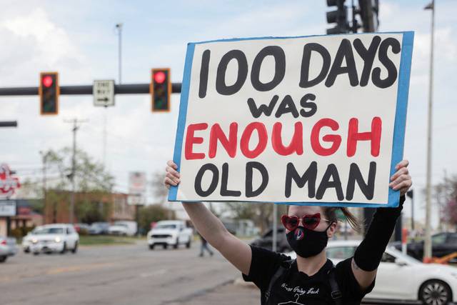 도널드 트럼프 미국 대통령의 취임 100일 기념 집회가 열린 29일(현지시간) 미시간주 머콤카운티 행사장 밖에서 한 여성이 ‘100일이면 충분하다, 늙은이’라고 적힌 팻말을 들고 있다. 로이터연합뉴스