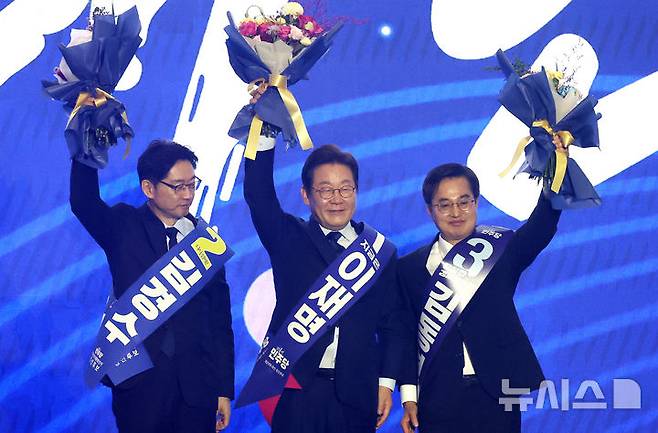 [고양=뉴시스] 조성우 기자 = 더불어민주당 제21대 대통령 선거 후보에 선출된 이재명(가운데) 후보가 27일 경기도 고양시 킨텍스에서 열린 제21대 대통령 선거 후보자 선출을 위한 수도권·강원·제주 합동연설회에서 김경수, 김동연 후보와 꽃다발을 들고 인사하고 있다. 2025.04.27. xconfind@newsis.com
