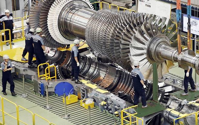 두산에너빌리티 직원들이 가스터빈 초도호기 최종조립을 위해 로터 블레이드를 케이싱에 설치하는 모습./두산에너빌리티