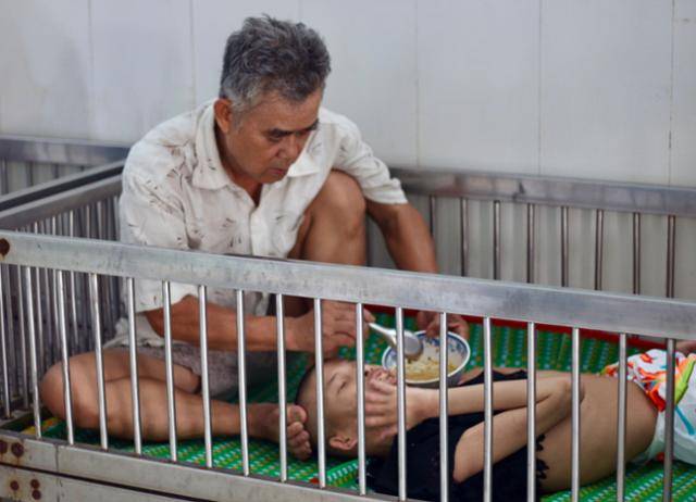 지난달 15일 베트남 호찌민시 구찌현 사회 보호 시설 '띠엔즈옌 복지원'에서 한 남성이 심각한 고엽제 피해 후유증을 앓고 있는 아들에게 밥을 떠 넣어주고 있다. 호찌민=허경주 특파원