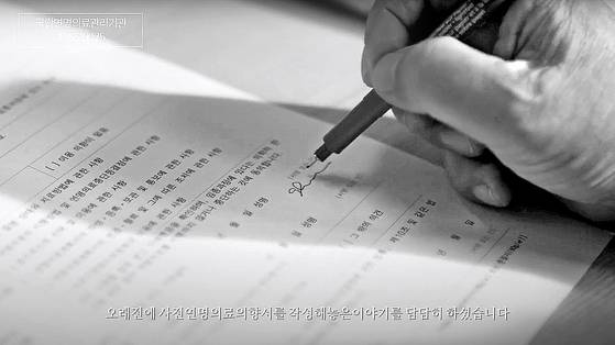 한 노인이 사전연명의료의향서를 작성하고 있다. 국립연명의료관리기관 홍보 영상 캡처