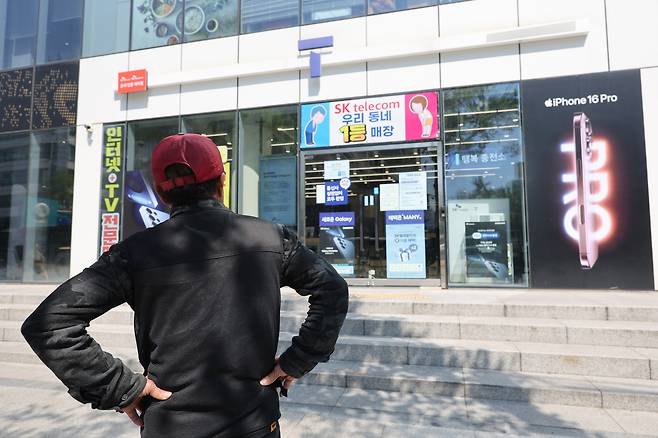 A person stands in front of an SK Telecom retail store in Seoul on May 2 to replace his subscriber identity module (SIM) card free of charge. [YONHAP]