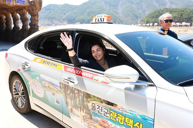 관광택시에 탄 외국인 관광객이 손을 흔들고 있다. 울진군 제공