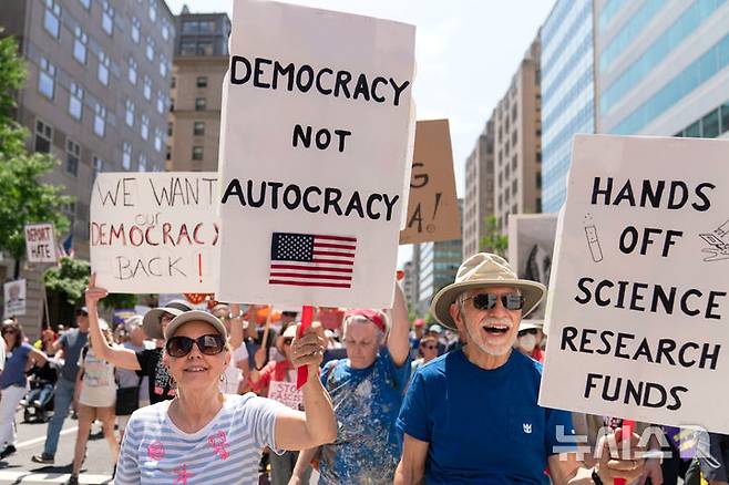 [워싱턴=AP/뉴시스]국제 노동절인 1일(현지 시간) 미국 전역에서는 도널드 트럼프 행정부에 반대하는 집회가 동시다발적으로 벌어진 가운데, 미국 워싱턴DC 백악관 인근에서 트럼프 대통령을 비판하는 구호를 든 집회 참가자들이 행진하고 있다. 2025.05.02.