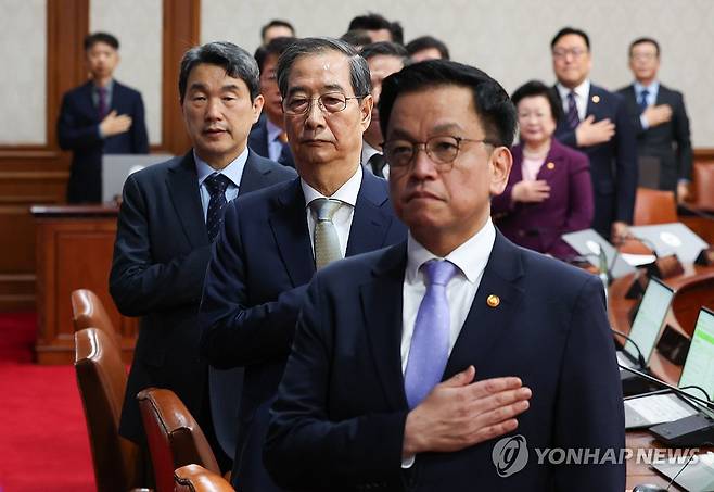 한덕수 권한대행 국무회의 주재 (서울=연합뉴스) 홍해인 기자 = 한덕수 대통령 권한대행 국무총리가 1일 정부서울청사에서 열린 국무회의에서 국기에 경례를 하고 있다. 오른쪽부터 최상목 부총리 겸 기획재정부 장관, 한 권한대행, 이주호 부총리 겸 교육부 장관. 2025.4.1 [대통령실통신사진기자단] hihong@yna.co.kr