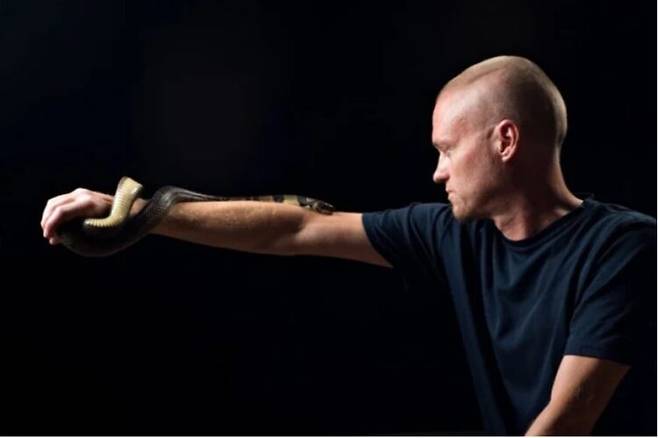 오른팔을 뻗은 채 코브라과의 독사인 가짜물코브라(Hydrodynastes gigas)를 팔 위에 올려놓은 팀 프리드. [사진=센티백스 제공]