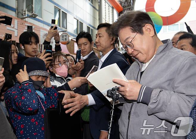 '골목골목 경청투어 : 동해안벨트편'에 나선 이재명 더불어민주당 대통령 후보가 3일 오전 강원 양양군 양양시장에서 한 시민 요청으로 책에 서명하고 있다. 2025.5.3/뉴스1 ⓒ News1 이재명 기자