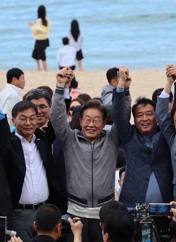 더불어민주당 이재명 대선 후보가 ‘골목골목 경청 투어’ 사흘째인 3일 강원도 강릉 안목해변에서 관계자들과 손을 들어 지지를 호소하고 있다. 연합뉴스