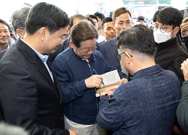 '골목골목 경청투어 : 접경벨트편'에 나선 이재명 더불어민주당 대통령 후보가 2일 오후 강원 인제군 북면 원통시장에서 한 지지자 요청으로 책에 서명하고 있다.&nbsp; &nbsp;뉴스1