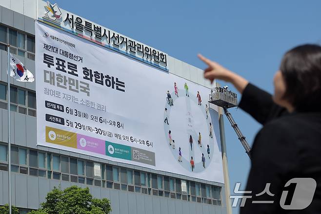 29일 오후 서울 종로구 창경궁로 서울시선거관리위원회 외벽에 관계자들이 제21대 대통령 선거 대형 홍보 현수막을 게시하고 있다. 제21대 대통령 선거는 오는 6월 3일 치러진다. 2025.4.29/뉴스1 ⓒ News1 박정호 기자