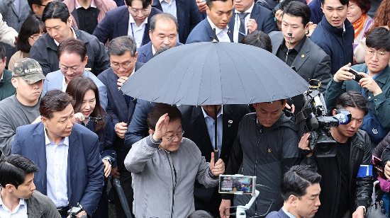 이재명 더불어민주당 대선 후보가 지난 3일 강원도 속초시 중앙재래시장에서 비가 그쳤음에도 우산을 쓴 채로 두터운 경호막에 둘러싸여 도민들을 향해 인사하고 있다. (사진=연합뉴스)