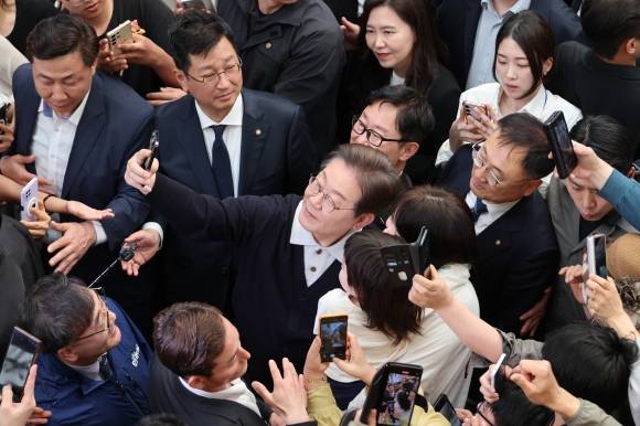 단양팔경에서 ‘경청 투어’ 이어가는 이재명 후보 - 이재명(가운데) 더불어민주당 대선후보가 ‘골목골목 경청 투어’ : 단양팔경 편‘에 나선 4일 충북 단양군 단양구경시장에서 한 아이를 안은 가족과 사진을 찍어주고 있다. 2025.5.4