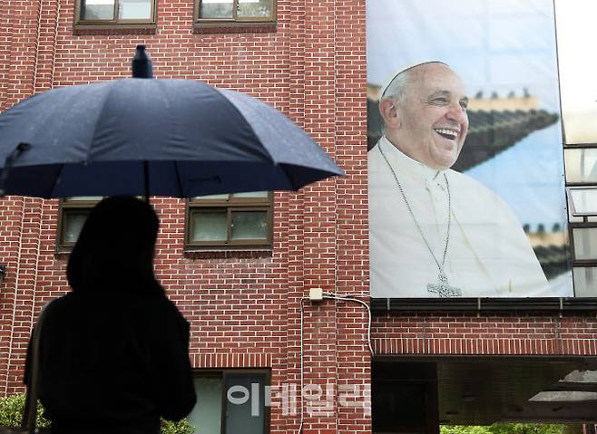 지난달 22일 서울 중구 명동성당의 건물에 걸린 프란치스코 교황의 사진을 한 신도가 바라보고 있다.(사진=김태형 기자)