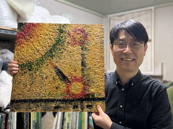 박준성 사단법인 트루 사무총장이 플라스틱 판자 '널'을 들고 서 있다. 트루는 기부받은 폐장난감에서 플라스틱을 분해해 가루를 낸 후, 고온으로 압착해 플라스틱 판자 널을 만들어낸다. 널은 가구, 인테리어 소재 등으로 쓰인다. 박 총장이 들어 올린 널에는 우연히 레고 사람 장난감 하나가 형체를 유지한 채 압착돼 있다. 김성진 기자