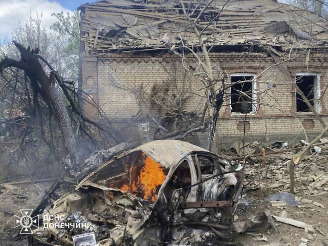 우크라이나 도네츠크 지역에서 28일(현지시간) 러시아군의 공습으로 파손된 한 주택 앞에서 자동차 1대가 불타고 있다. 러시아가 28일 나치 독일에 대한 승전 기념일을 맞아 5월8일부터 10일까지 우크라이나에서 전면 휴전을 선언했다./AP=뉴시스