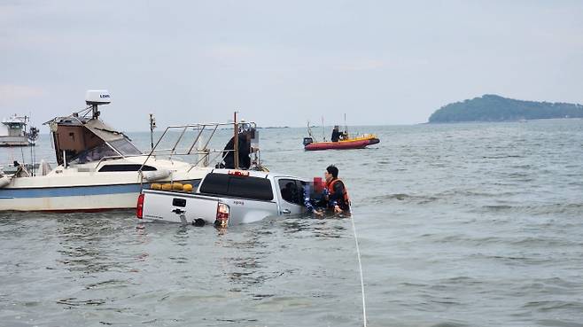 인천해경 하늘바다파출소 경찰관들이 5일 인천 중구 덕교동 거잠포선착장 인근 해상에서 침수된 차량에 갇힌 남성을 구조하고 있다./사진=인천해양경찰서