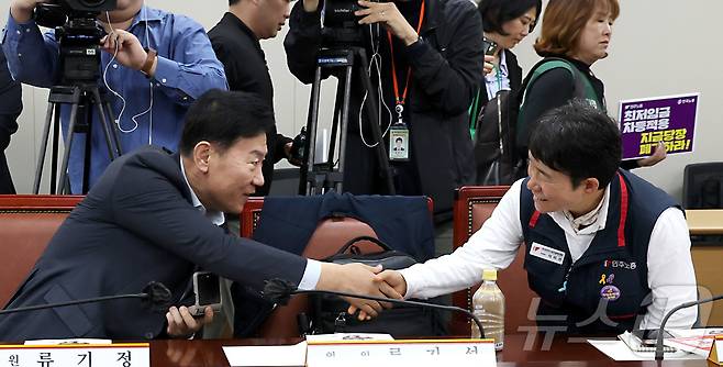 류기정 최저임금위원회 사용자위원과 이미선 근로자위원이 지난달 22일 세종시 어진동 정부세종청사 고용노동부에서 열린 2026년 최저임금위원회 제1차 전원회의에 참석하며 악수를 나누고 있다. 2025.4.22/뉴스1 ⓒ News1 김기남 기자