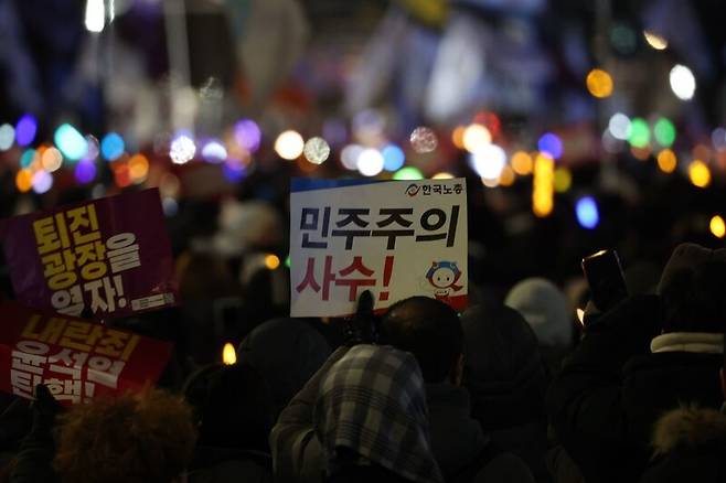 지난해 12월7일 오후 서울 여의도 국회 앞에서 열린 ‘내란죄 윤석열 퇴진! 국민주권 실현! 사회 대개혁! 범국민 촛불대행진’에서 참석자가 “민주주의 사수” 손팻말을 들고 있다. 연합뉴스