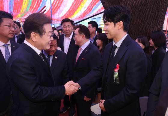 이재명 더불어민주당 대선후보와 가수 이승기가 불기 2569(2025)년 부처님오신날을 맞은 5일 서울 종로구 조계사 대웅전 앞에서 열린 부처님 오신날 봉축법요식에서 악수를 나누고 있다. 대통령실사진기자단