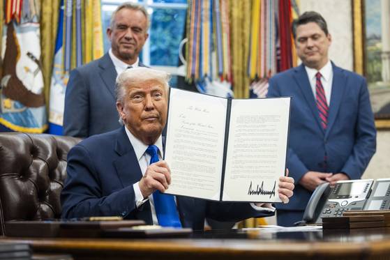 도널드 트럼프 미국 대통령이 5일(현지시간) 백악관 집무실에서 보건과 의약품과 관련한 행정명령에 서명한 뒤 이를 언론에 들어보이고 있다. 트럼프 대통령은 이날 서명식에서 갑자기 자신의 최측근인 빈스 헤일리 국내정책위원장(트럼프 대통령 우측)을 호명해 언론 카메라 앞에 서도록 했다. EPA=연합뉴스