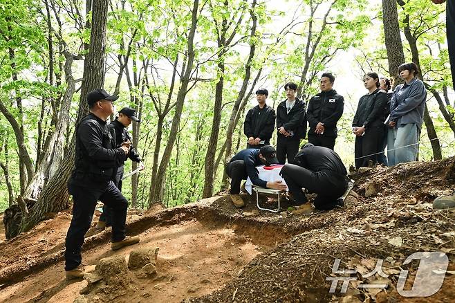 국방부유해발굴감식단(국유단)은 2일 홍보대사 최태성 역사 커뮤니케이터와 국방부 및 국가보훈부 2030 자문단이 경기도 가평군 내 6·25 전사자 유해발굴 현장을 방문했다고 밝혔다. 참석자들이 발굴현장에서 실제 수습된 유해를 입관하고 태극기 관포하는 모습을 지켜보고 있다. (국방부 제공. 재판매 및 DB 금지) 2025.5.2/뉴스1