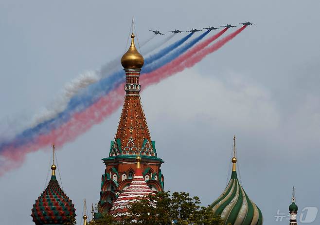 러시아의 전투기 수호이(Su)-25 6대가 지난해  제2차 세계대전 승전 79주년을 기념해 모스크바 붉은 광장에서 열린 열병식에서 편대 비행을 하며 러시아 국기 색깔인 흰·파란·빨간색 연기를 뿜어내고 있다. ⓒ 로이터=뉴스1