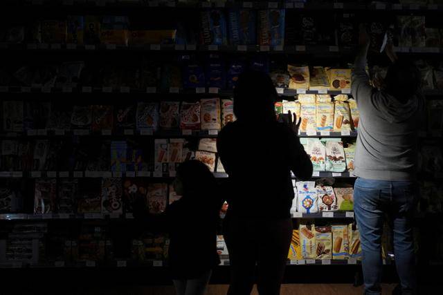 스페인·포르투갈에 전례 없는 대정전이 발생했던 지난달 28일 시민들이 스페인 바르셀로나의 한 상점에서 휴대폰 불빛에 의지해 상품을 구매하고 있다. 바르셀로나=로이터 연합뉴스