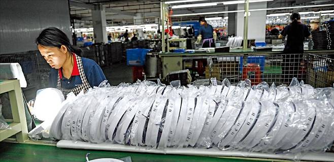 < 우회수출 통로 찾는 中 제조업 > 중국 남부 광둥성 중산시에 있는 LED(발광다이오드) 조명 제조업체의 조립 라인에서 한 직원이 일하고 있다. 145%의 추가 관세로 미국 수출이 막히자 중국 수출 기업 상당수는 일본, 동남아시아 등 우회 수출 통로를 찾고 있다.  AFP연합뉴스