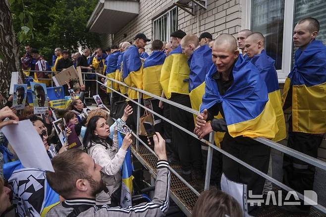 [우크라이나=AP/뉴시스] 6일(현지 시간) 우크라이나의 장소 미공개 지역에서 러시아와의 포로 교환을 통해 석방된 우크라이나 군인들에게 실종되거나 억류 중인 군인 가족들이 사진을 보여주며 생사를 확인하고 있다. 2025.05.07.