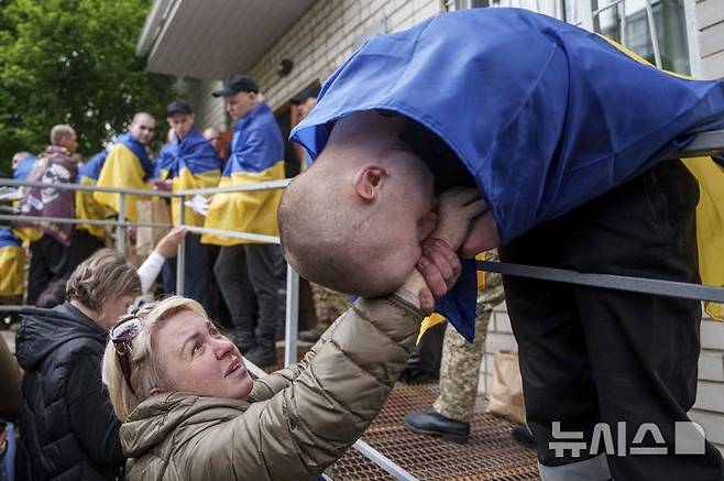 [우크라이나=AP/뉴시스] 6일(현지 시간) 러시아와의 포로 교환을 통해 석방된 우크라이나 군인이 장소가 알려지지 않은 곳에 도착해 한 여성의 손에 입 맞추고 있다. 양국은 이날 205명의 포로를 교환했다. 2025.05.07.