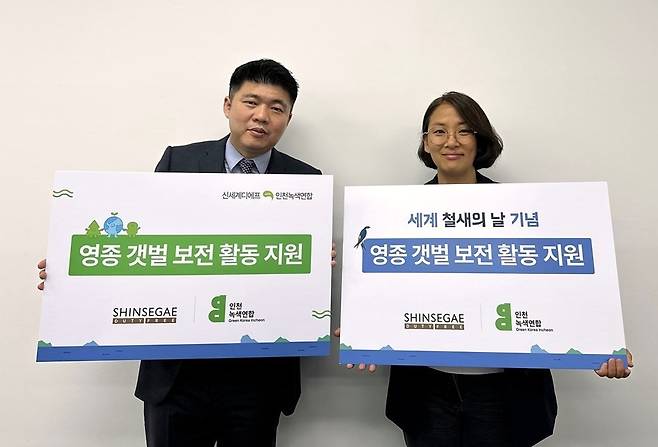 서영국 신세계면세점 인천공항점장(왼쪽)과 신정은 인천녹색연합 사무처장이 영종도 갯벌 보전 활동 지원금 전달식에서 기념 촬영을 하고 있다. (신세계면세점 제공).