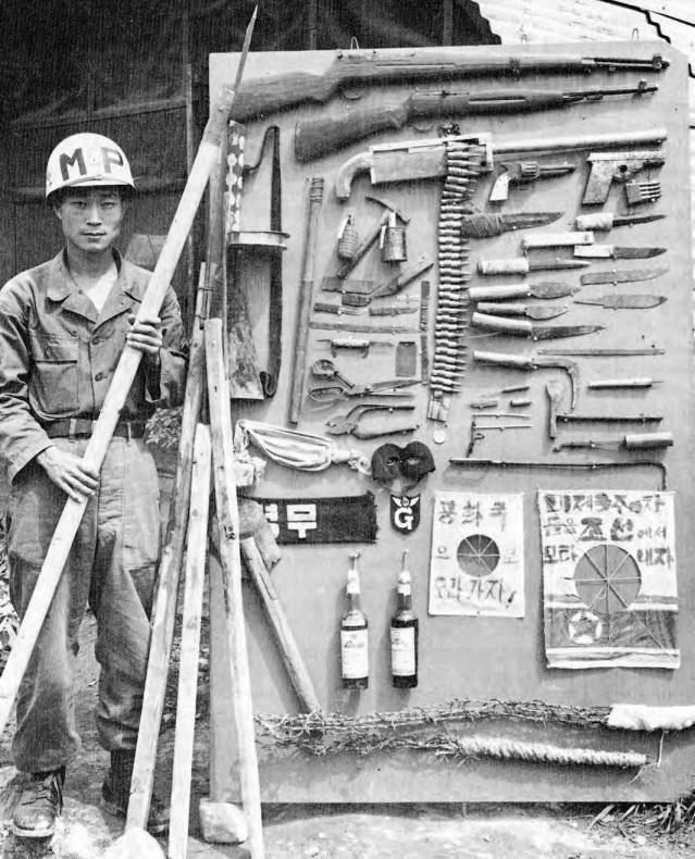 거제 포로수용소가 공산군 포로에게 압수한 물품. 소총, 탄약, 흉기, 죽창 등의 무기가 보인다. 월터 허미스 'Truce tent and fighting front'