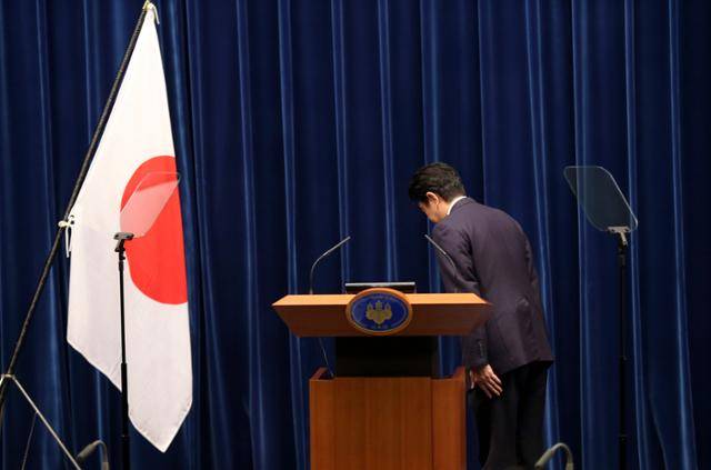 아베 신조 당시 일본 총리가 2015년 8월 14일 도쿄 총리 관저에서 '제2차 세계대전 패전 70년 담화'를 발표하기에 앞서 일장기에 예를 표하고 있다. 도쿄=AP 연합뉴스