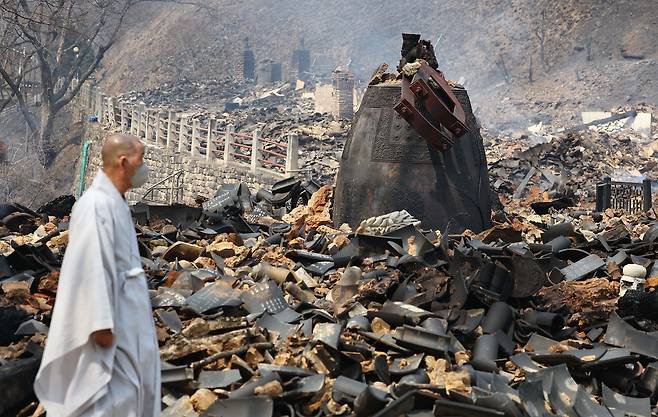 A Buddhist monk walks past the remains of the destroyed buildings at the Gounsa Temple in Uiseong-gun, North Gyeongsang Province, on March 26. (Lee Sang-sub/The Korea Herald)